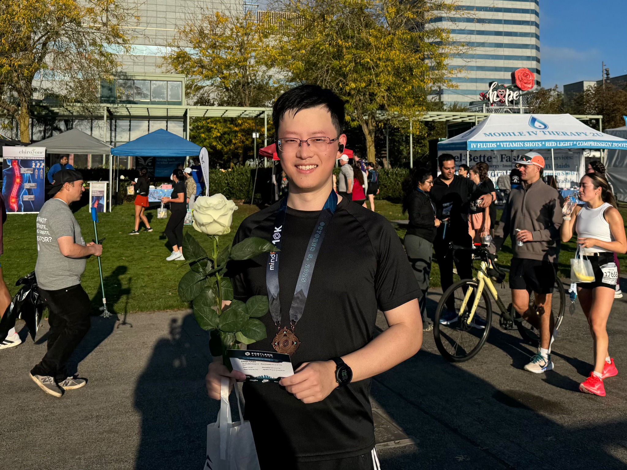Zihan smiling at a running event, wearing a medal and holding a rose